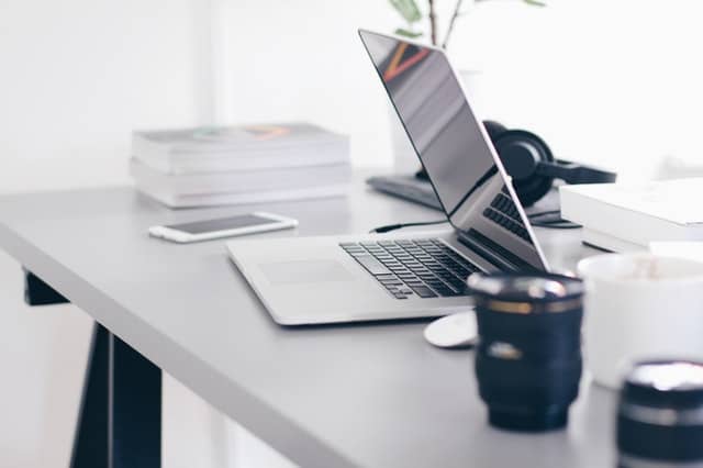 books and a computer and a mug on a table showcasing home working